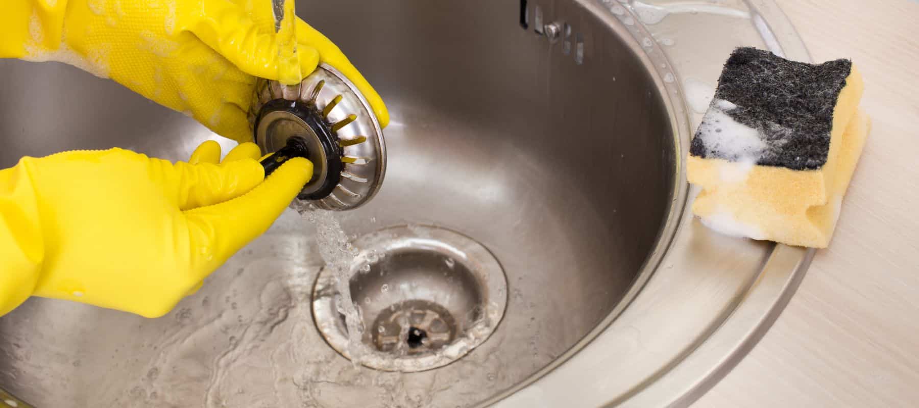 person cleaning a drain cover with a sponge