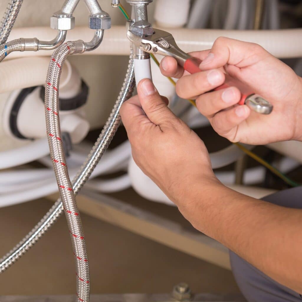 using a wrench to tighten a hose on a tub