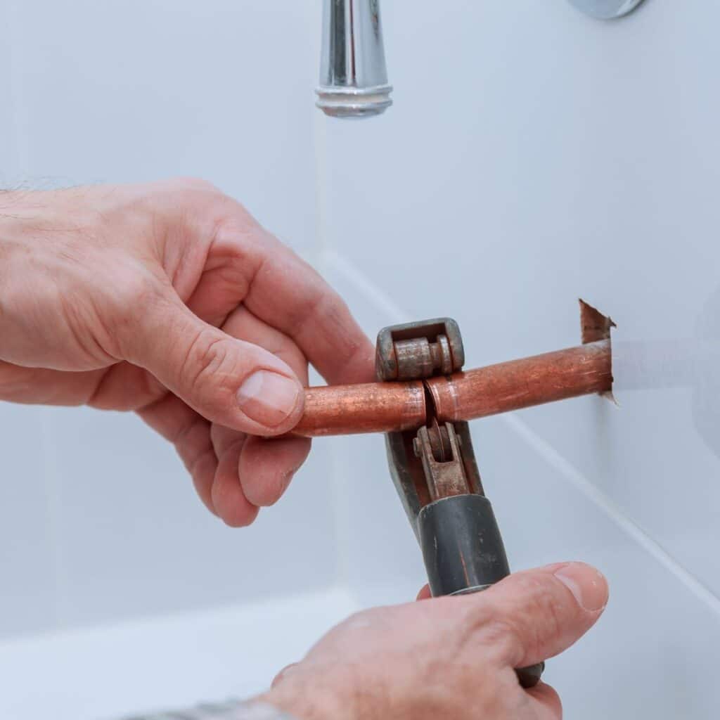 plumbing using a pipe cutter to shorten a copper pupe
